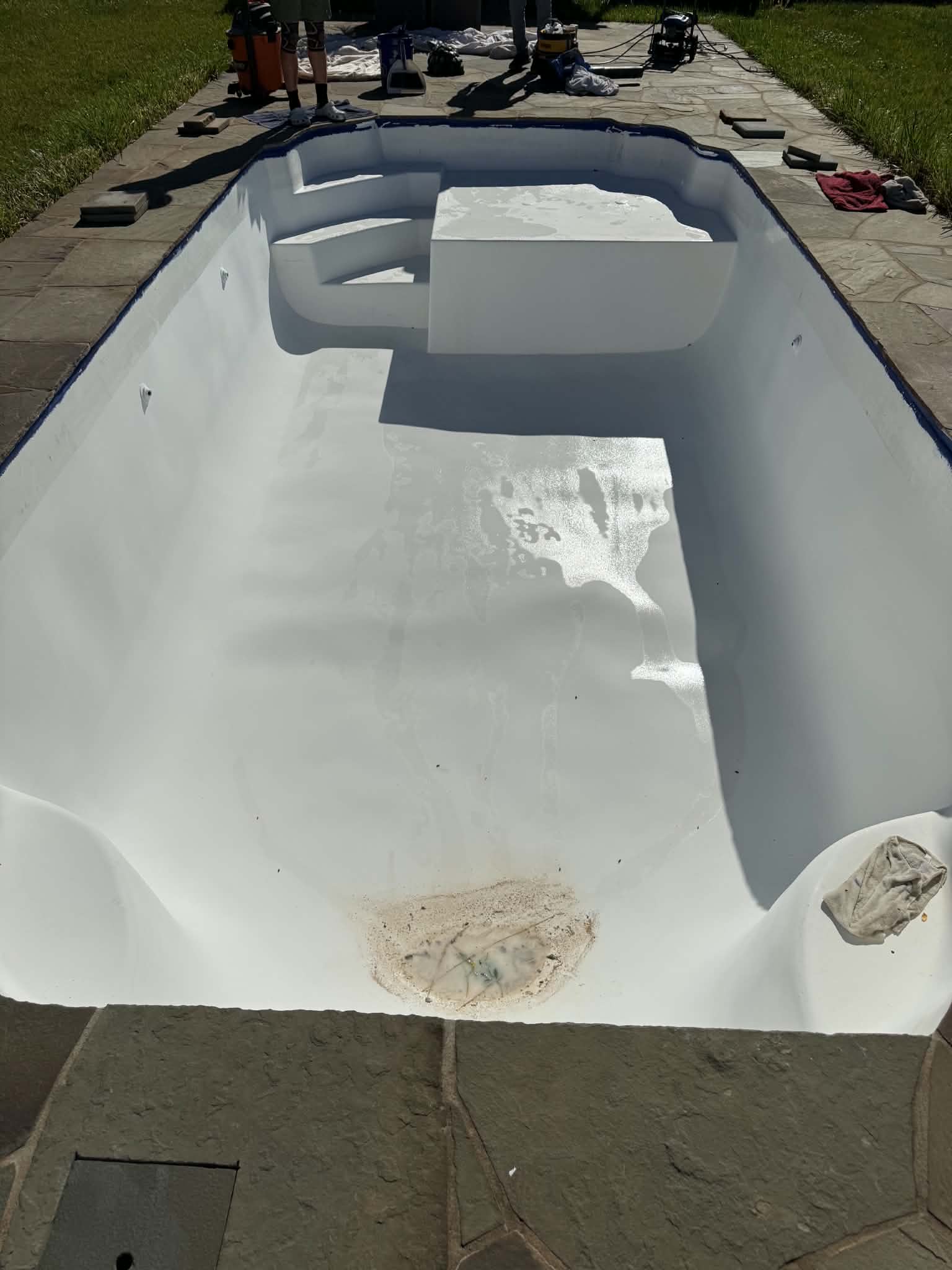 Rectangular fiberglass pool with damaged patches before resurfacing