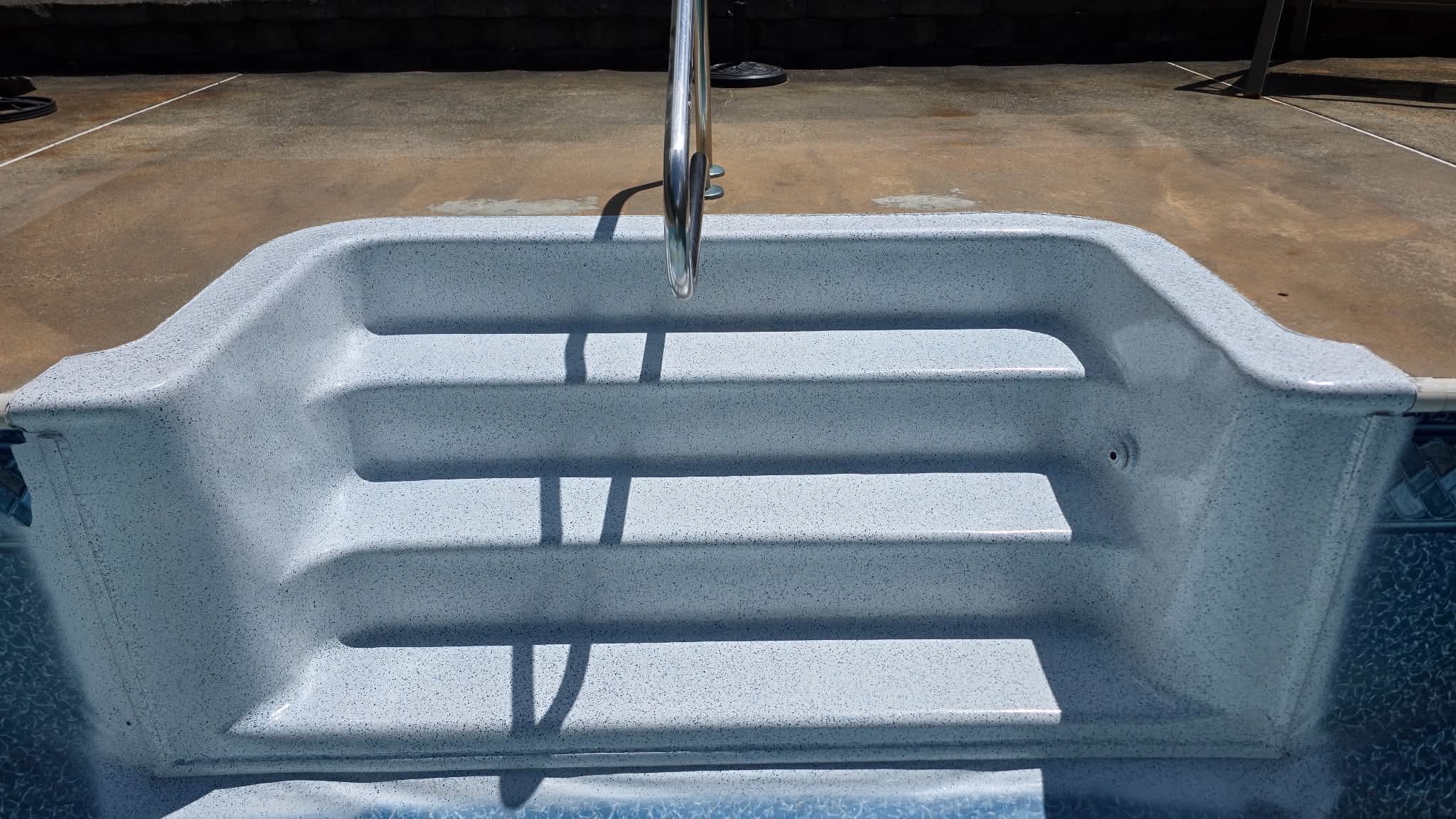 Wide view of gray-speckled fiberglass pool steps