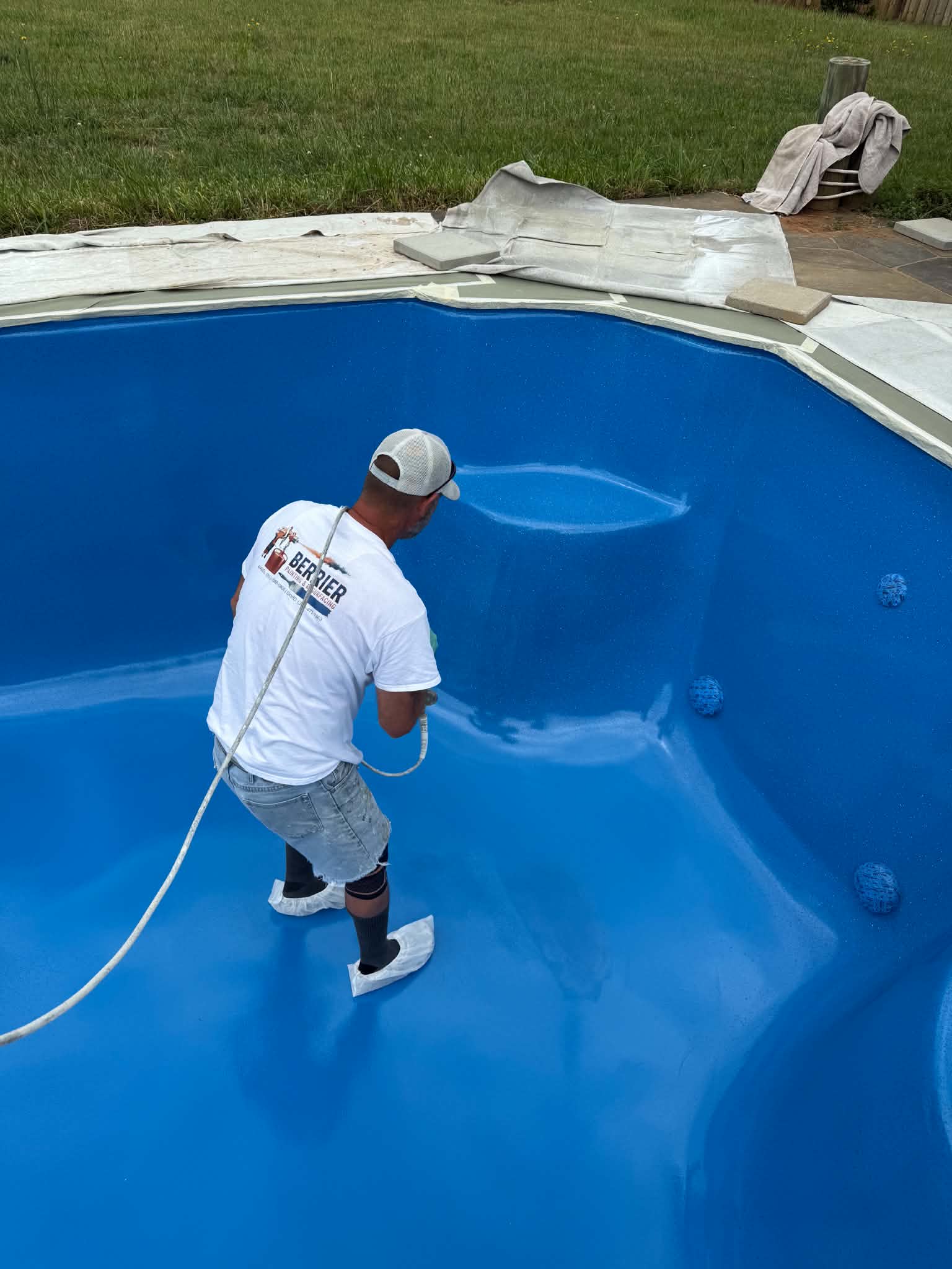 Technician spraying a royal-blue pool finish