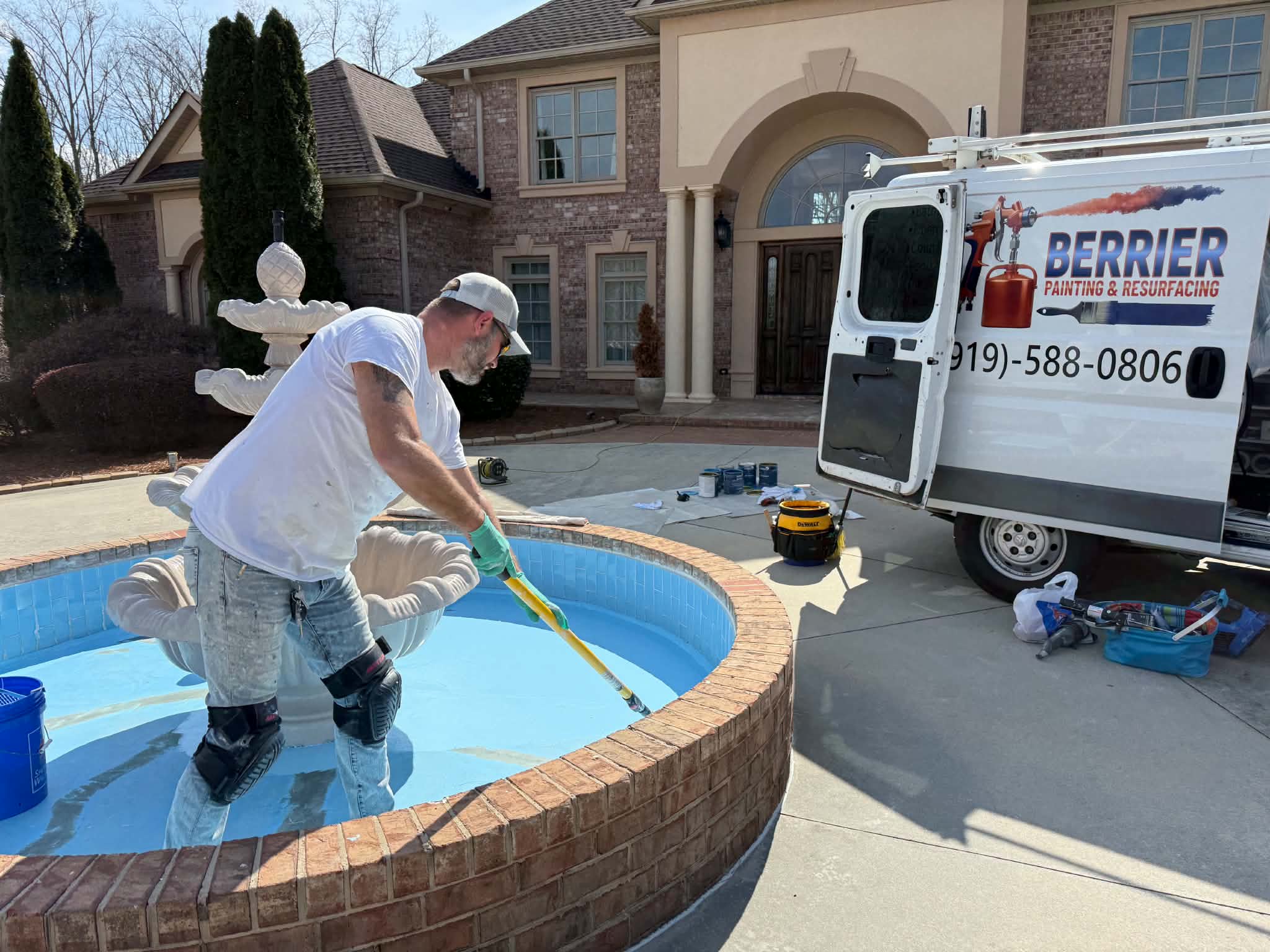 Technician resurfacing a circular spa beside the Berrier van