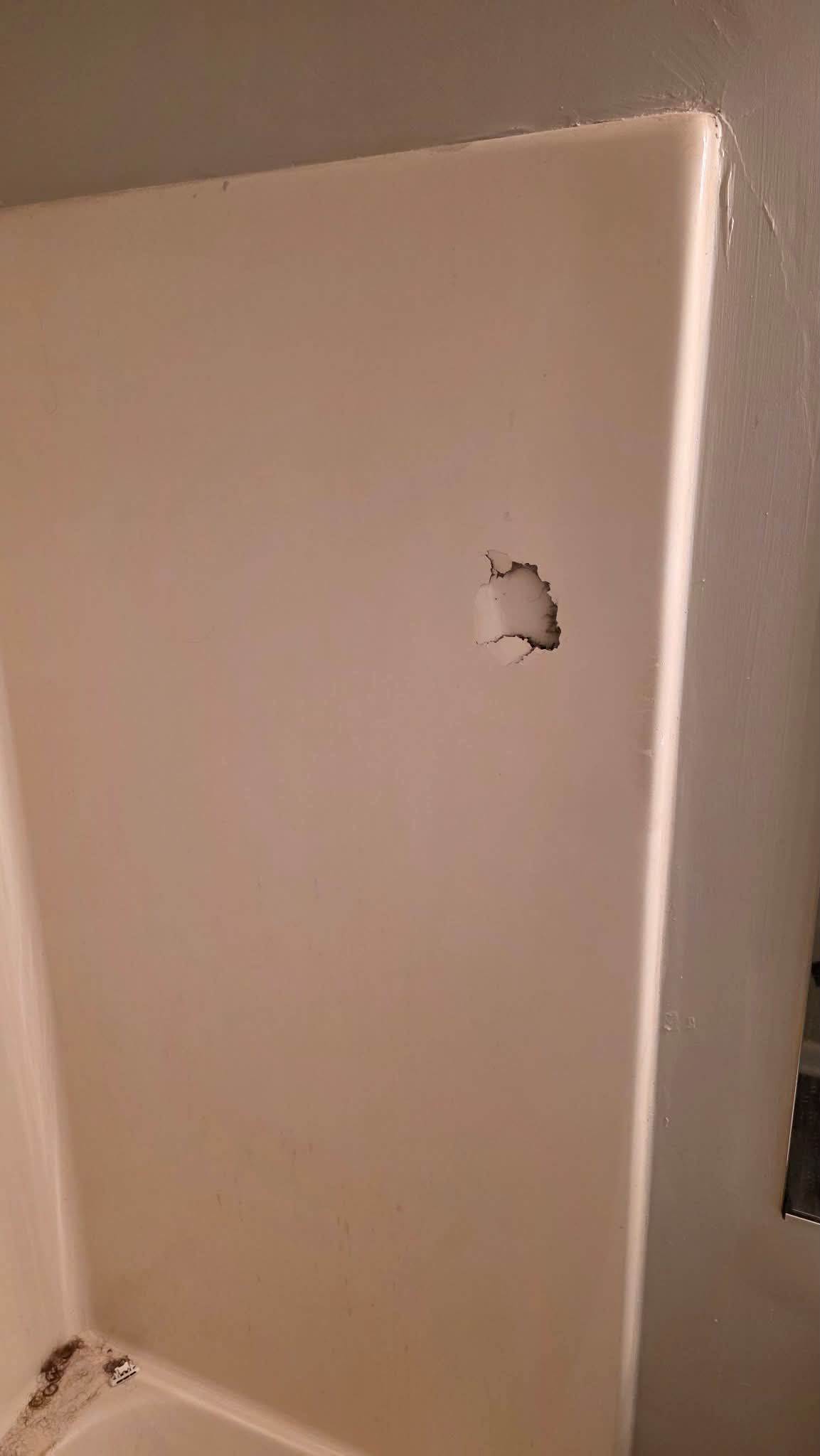 Chip in a bathtub wall before repair