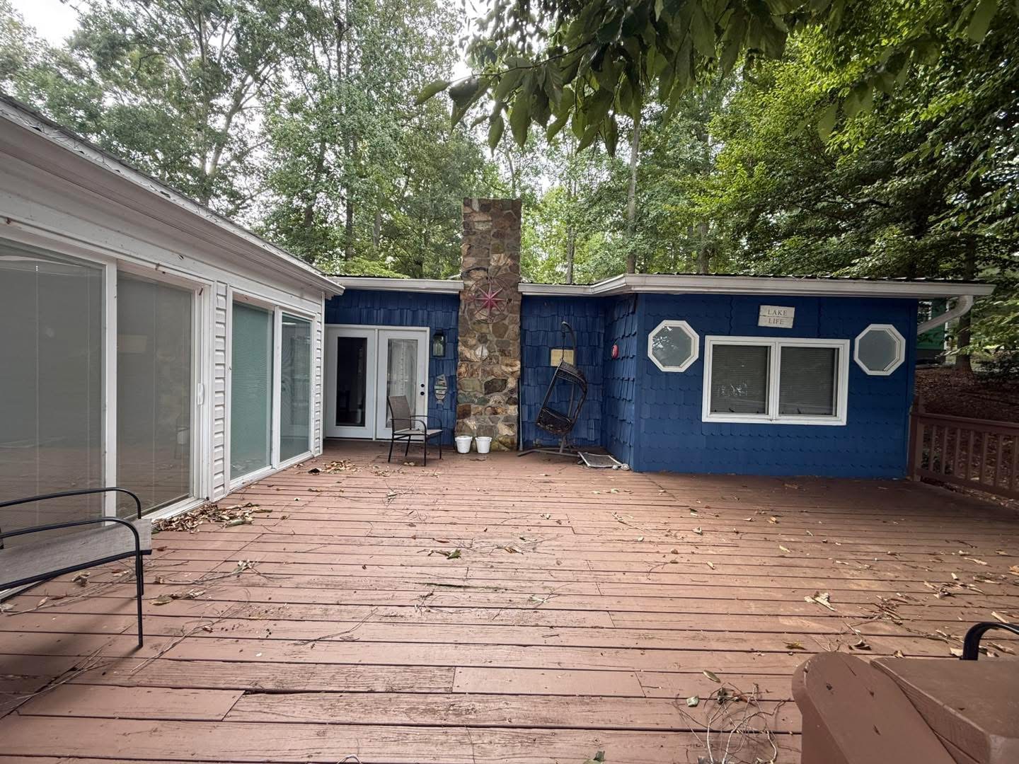 Deck area with blue shingle siding and stone chimney before painting