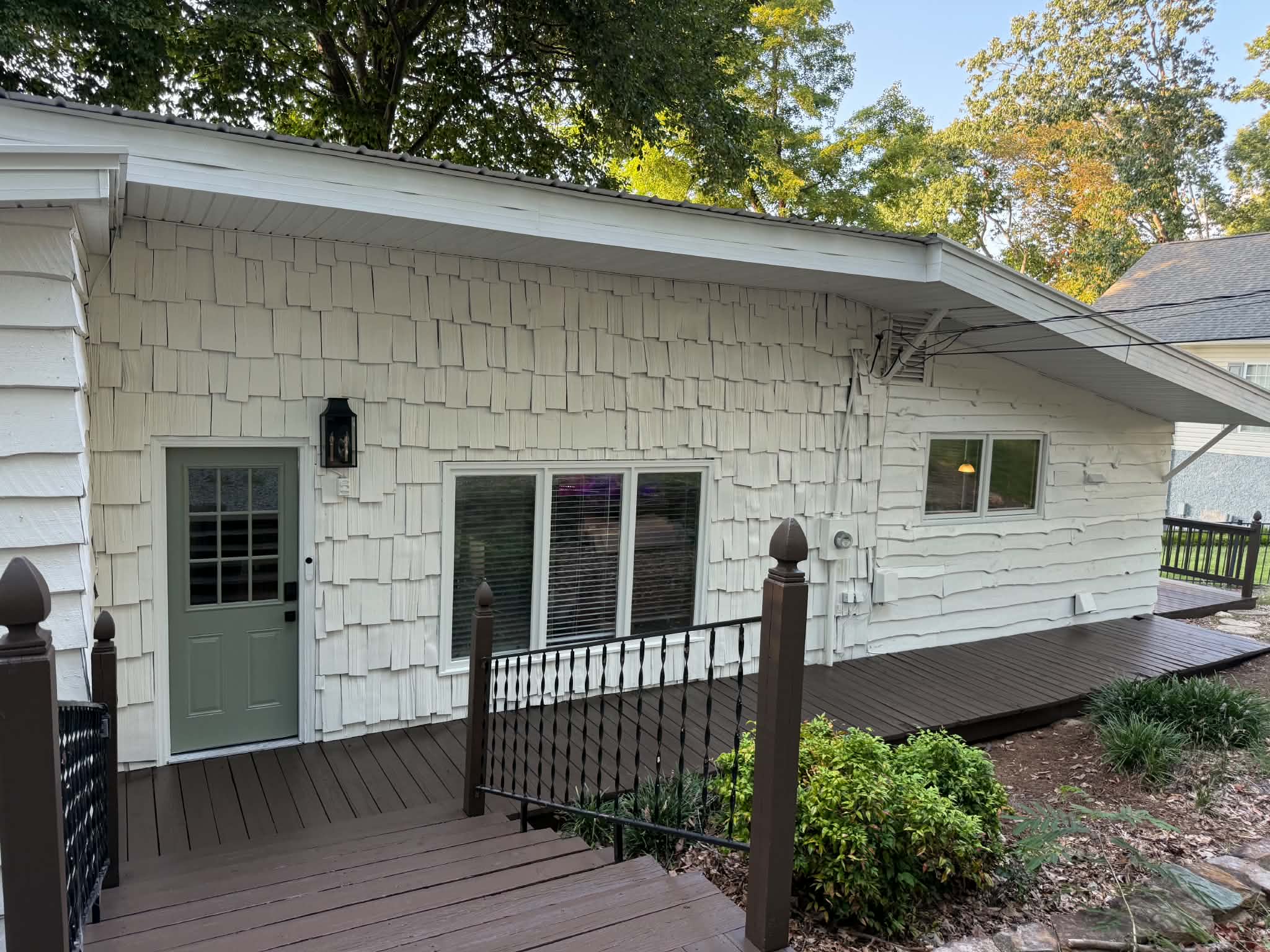 White shingle siding and trim with a muted green exterior door
