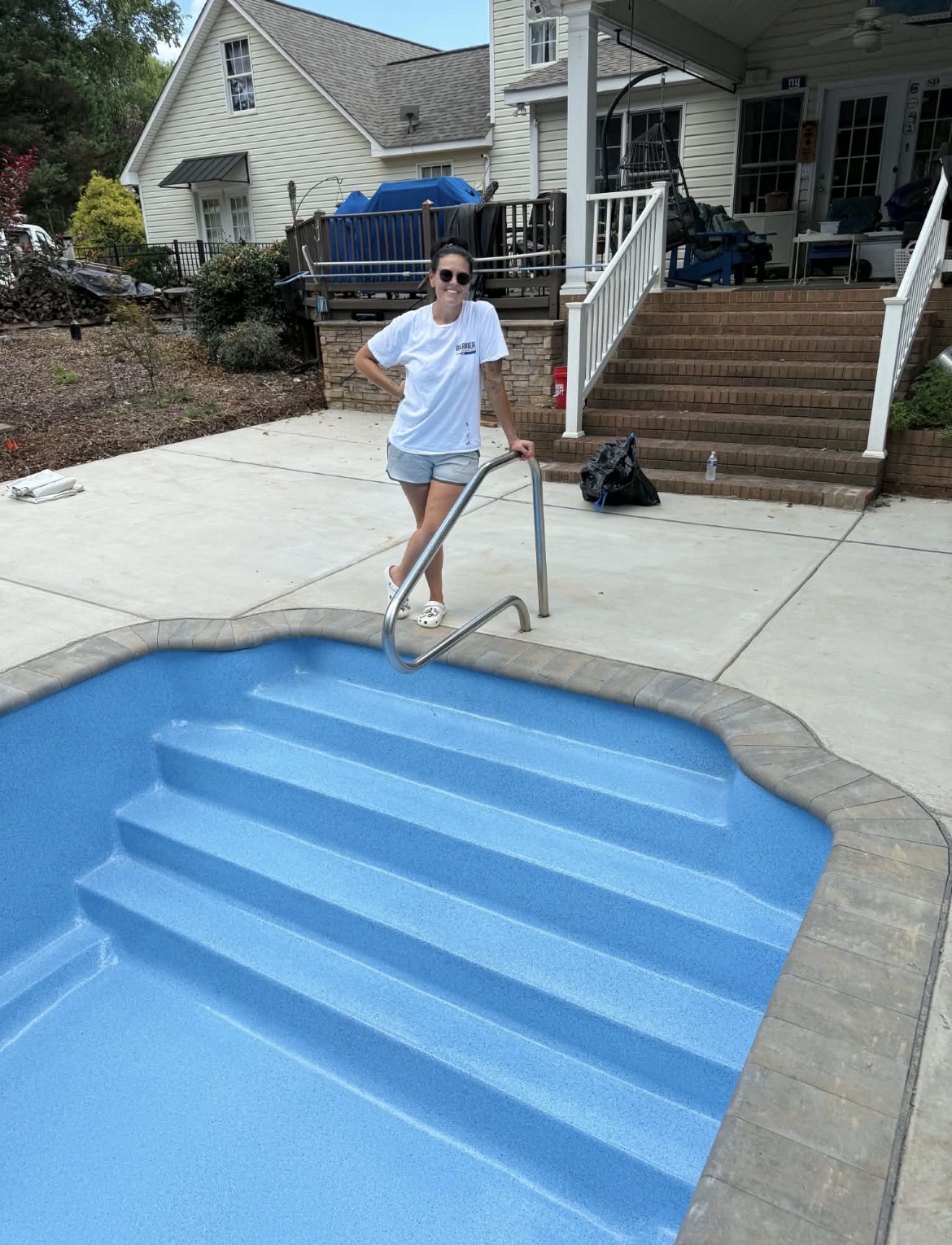Angel Berrier standing beside the steps of a resurfaced blue swimming pool